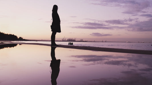 Young Female Fashion Influencer in Autumn Coat Standing on Beach Seashore during Golden Sunset on Beautiful Calm Afternoon