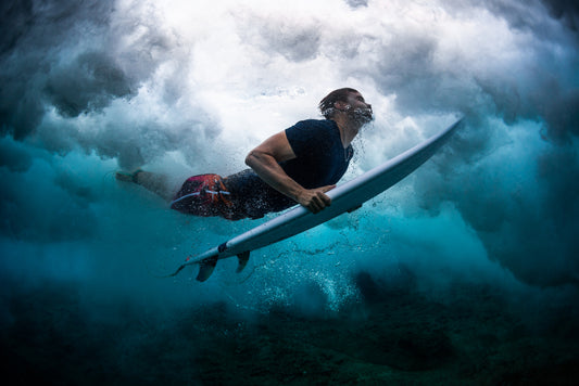 Young male surfer dives under the broken wave with his surfboard