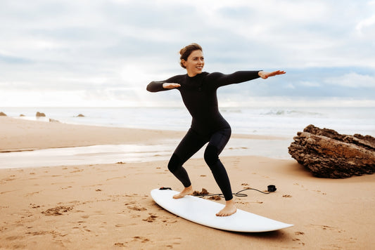 Fit young woman instructor demonstrating how to stand up on surfboard, preparing and practicing on surfboard on beach by seaside, free space