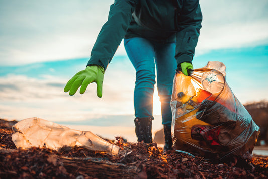 A volunteer collects garbage on a muddy beach. Close-up.