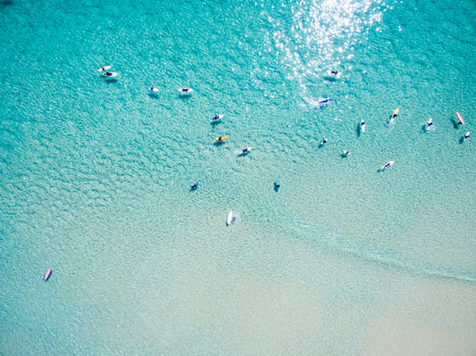 An aerial view of surfers waiting for a wave in the ocean on a clear day